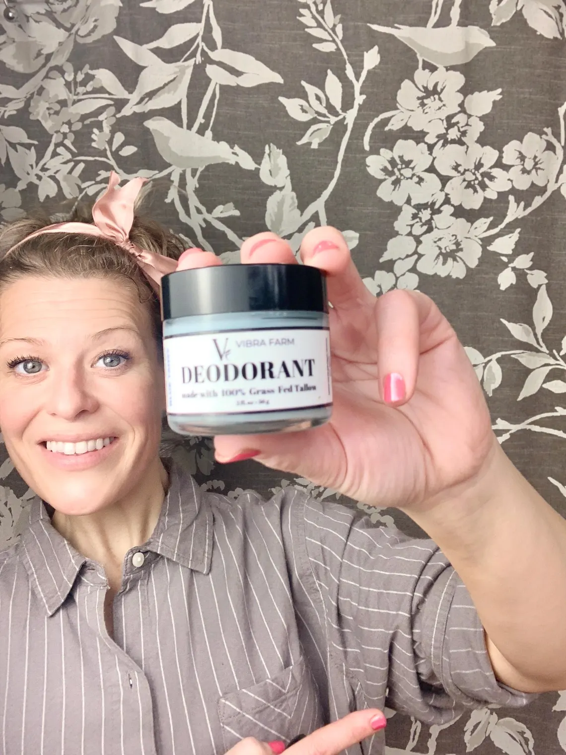 Image of Blue Tansy Grass Fed Tallow Deodorant being held in her hand as she poses with a nervous smile.