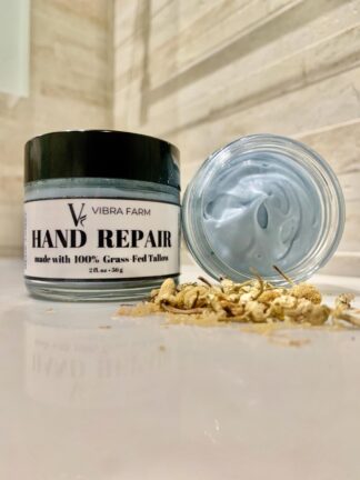 Vibra Farm Hand Repair Cream with Blue Tansy shown on a beautiful marble sink with white stone walls behind.